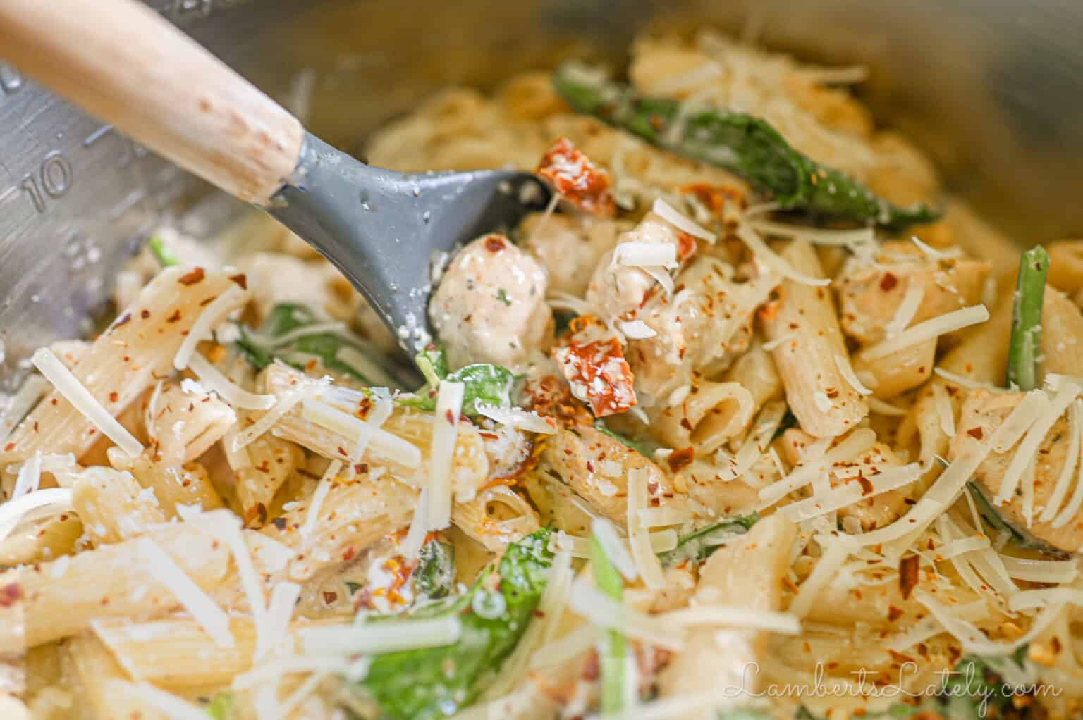scooping a spoonful of marry me chicken pasta.