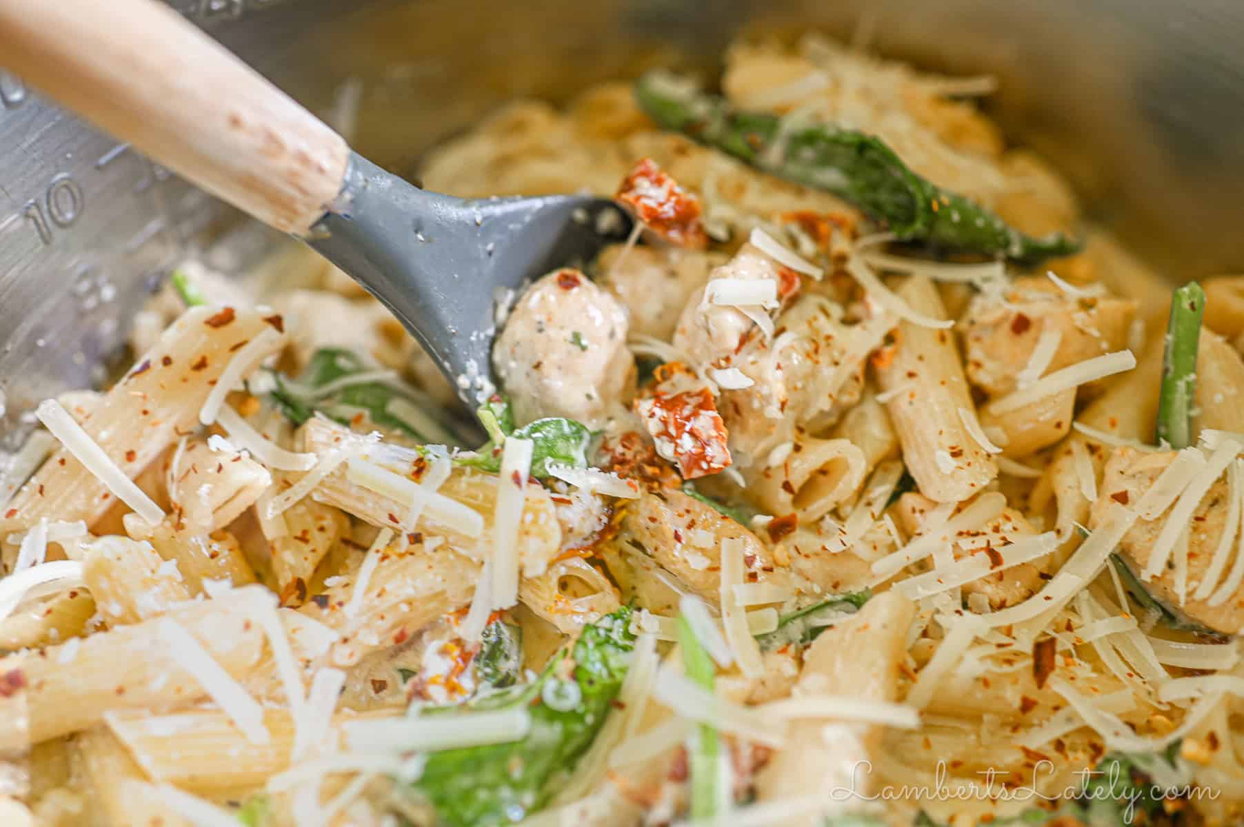 scooping a spoonful of marry me chicken pasta.