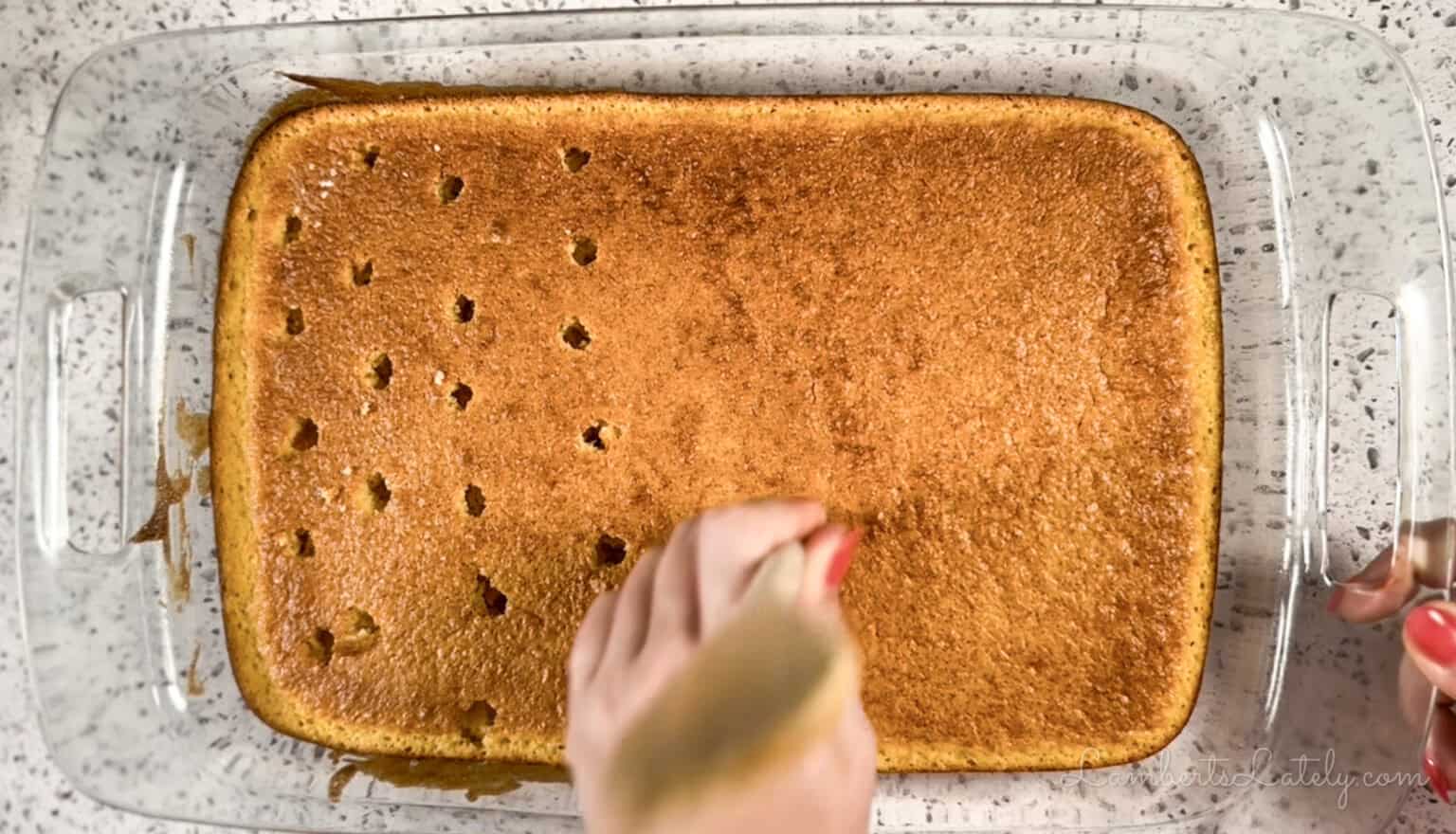 poking holes in a sheet cake with the back of a wooden spoon.