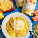 Lemon Dump Cake with lemon slices and Betty Crocker Lemon Creme mix on a blue background.