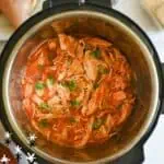 Instant Pot Salsa Chicken in a black pot with spices and herbs.