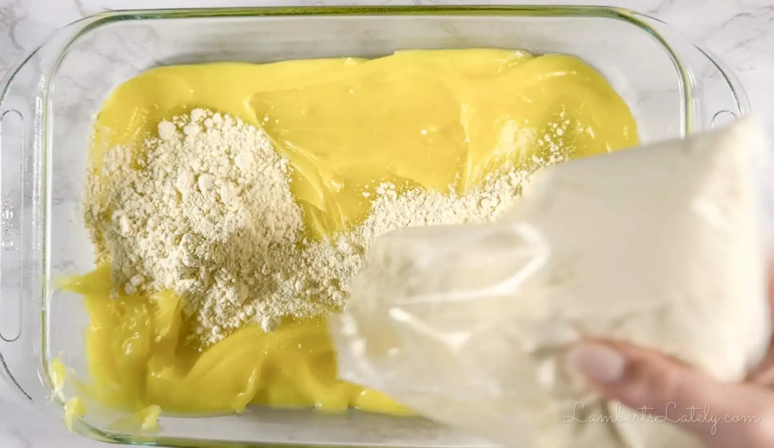 pouring cake mix over pie filling in a baking dish.