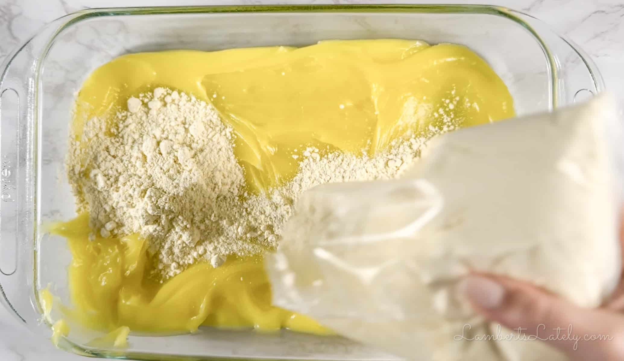 pouring cake mix over pie filling in a baking dish.