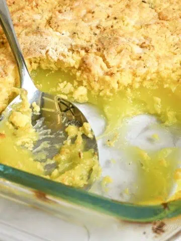 a spoon in a baking dish of lemon dump cake.