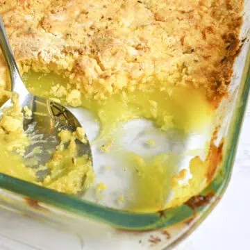 looking into a dish of lemon dump cake, with a pie filling layer and golden cake mix layer, spoon in baking dish.