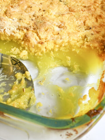looking into a dish of lemon dump cake, with a pie filling layer and golden cake mix layer, spoon in baking dish.