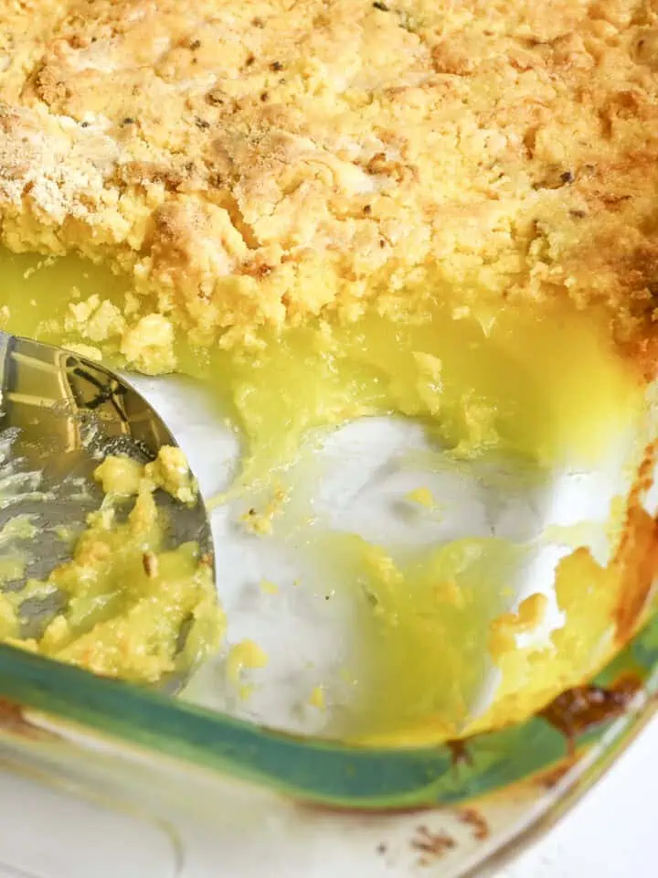 looking into a dish of lemon dump cake, with a pie filling layer and golden cake mix layer, spoon in baking dish.