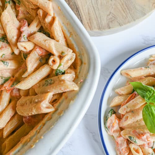 casserole dish full of boursin cheese pasta next to a serving on a plate.