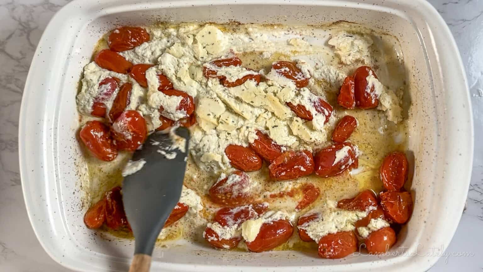 stirring cheese and tomatoes in a baking dish.
