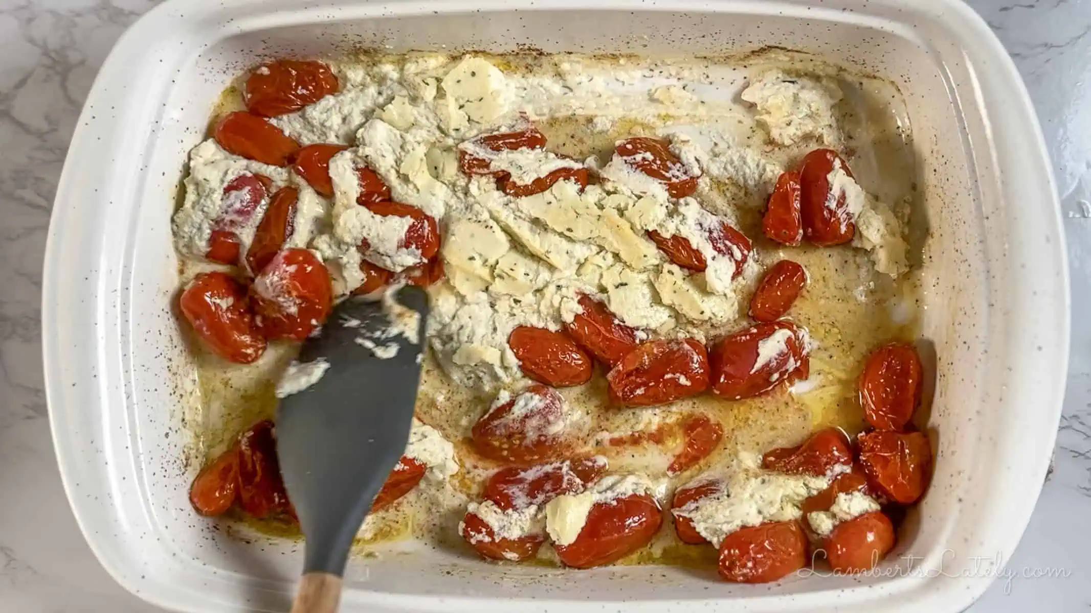 stirring cheese and tomatoes in a baking dish.