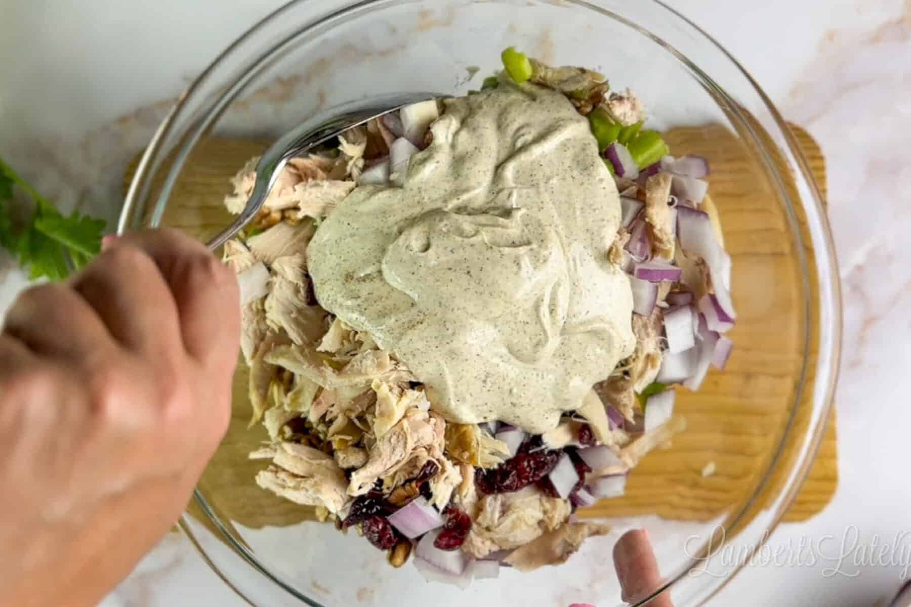 adding dressing to chicken salad mixture.