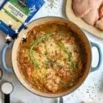 French Onion Chicken Bake in a blue casserole dish with fresh herbs and ingredients around.