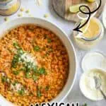 Mexican street corn casserole in a white dish with lime wedges and toppings.