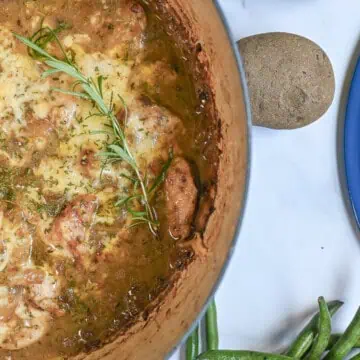 french onion chicken bake in a cast iron pan, with green beans and potatoes next to it.
