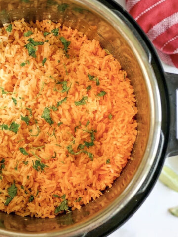 mexican rice topped with cilantro in an instant pot, with limes and a towel next to it.