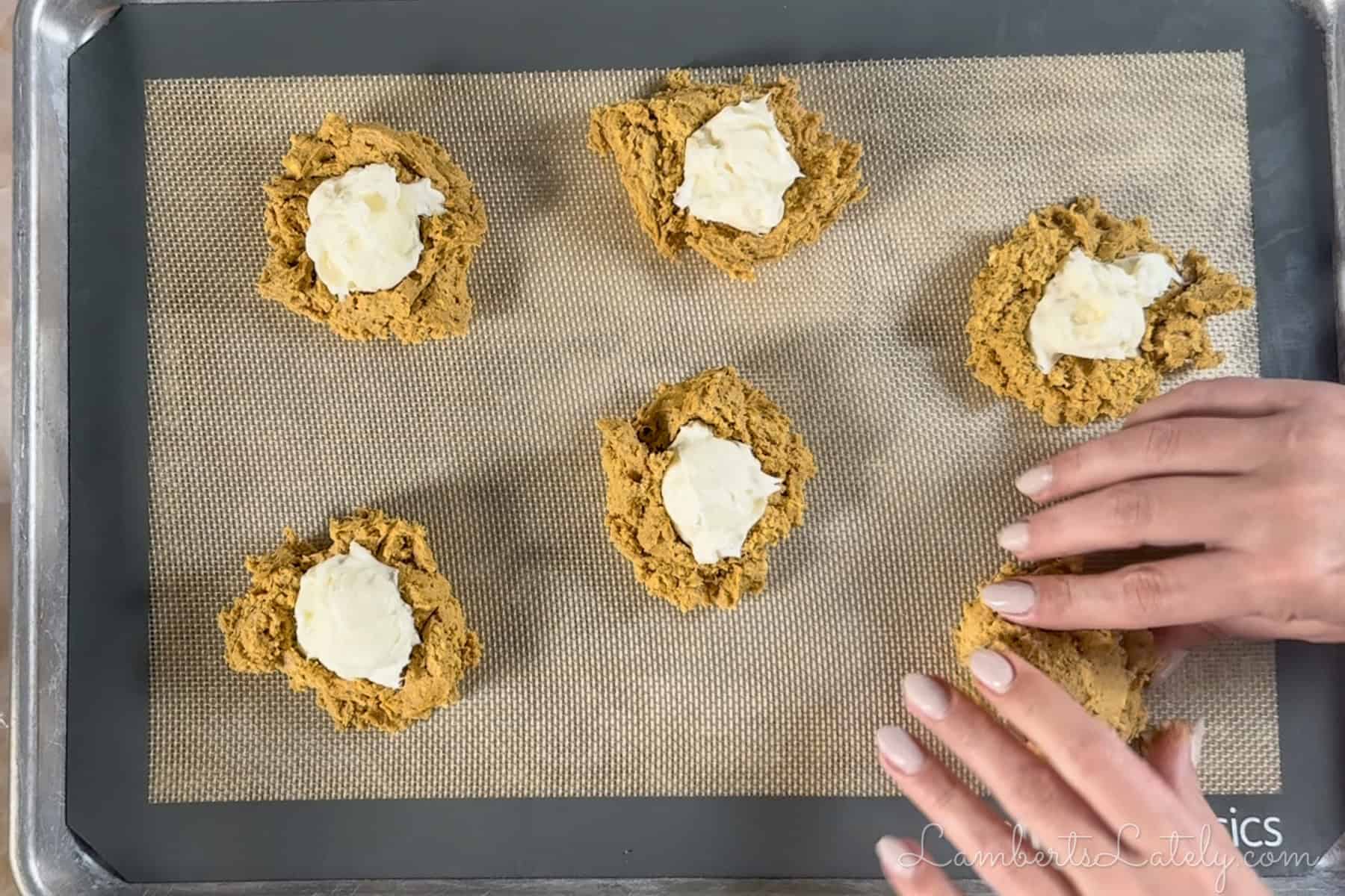 stuffing pumpkin cookies with cheesecake filling.