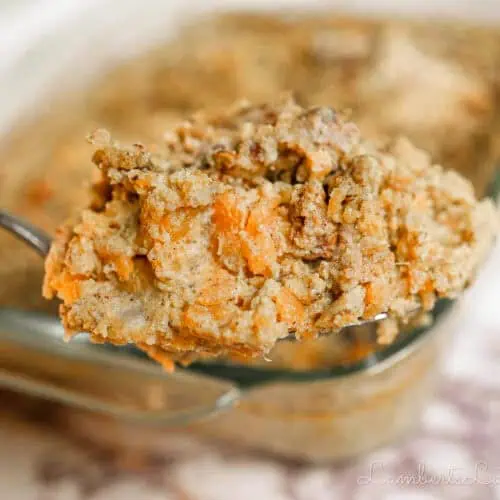 holding a spoonful of sweet potato casserole in front of a casserole dish.