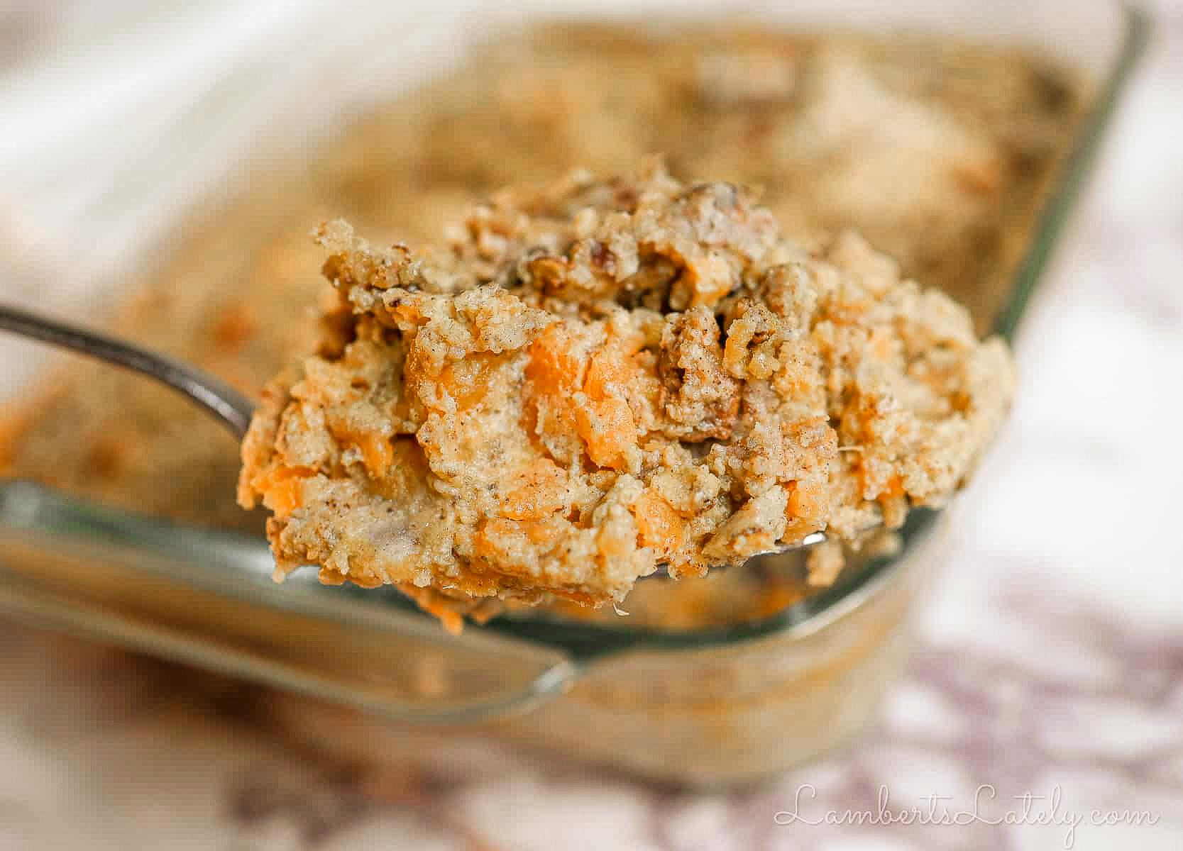holding a spoonful of sweet potato casserole in front of a casserole dish.