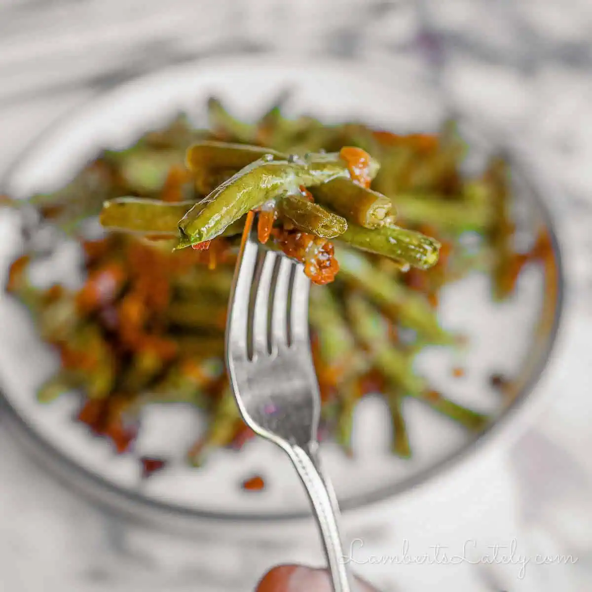 holding a fork-full of crack green beans with bacon and glaze.