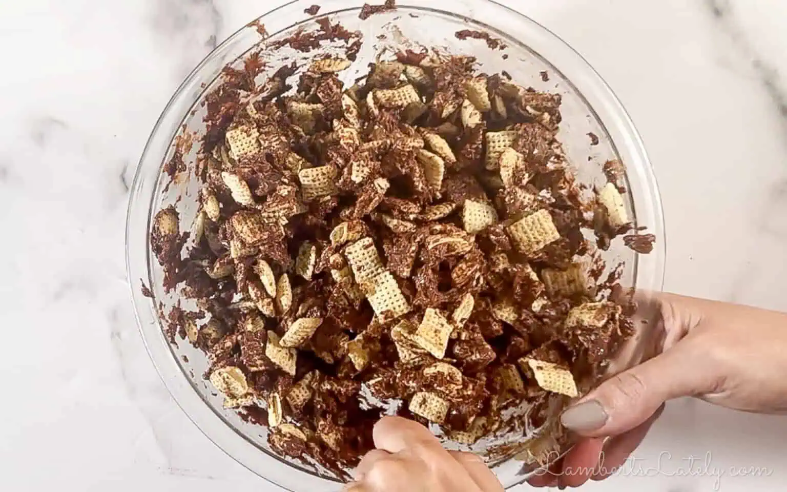 adding chex to the chocolate mixture in the bowl.