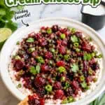 Cranberry jalapeño dip with fresh herbs and lime slices on a white plate.
