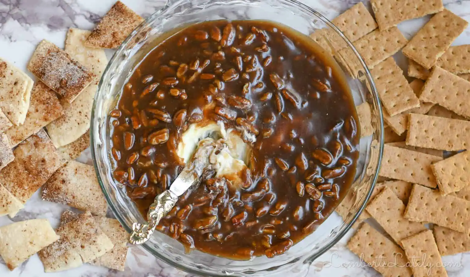 pecan pie dip in a pie dish, with a knife, surrounded by pie crust and graham cracker dippers.