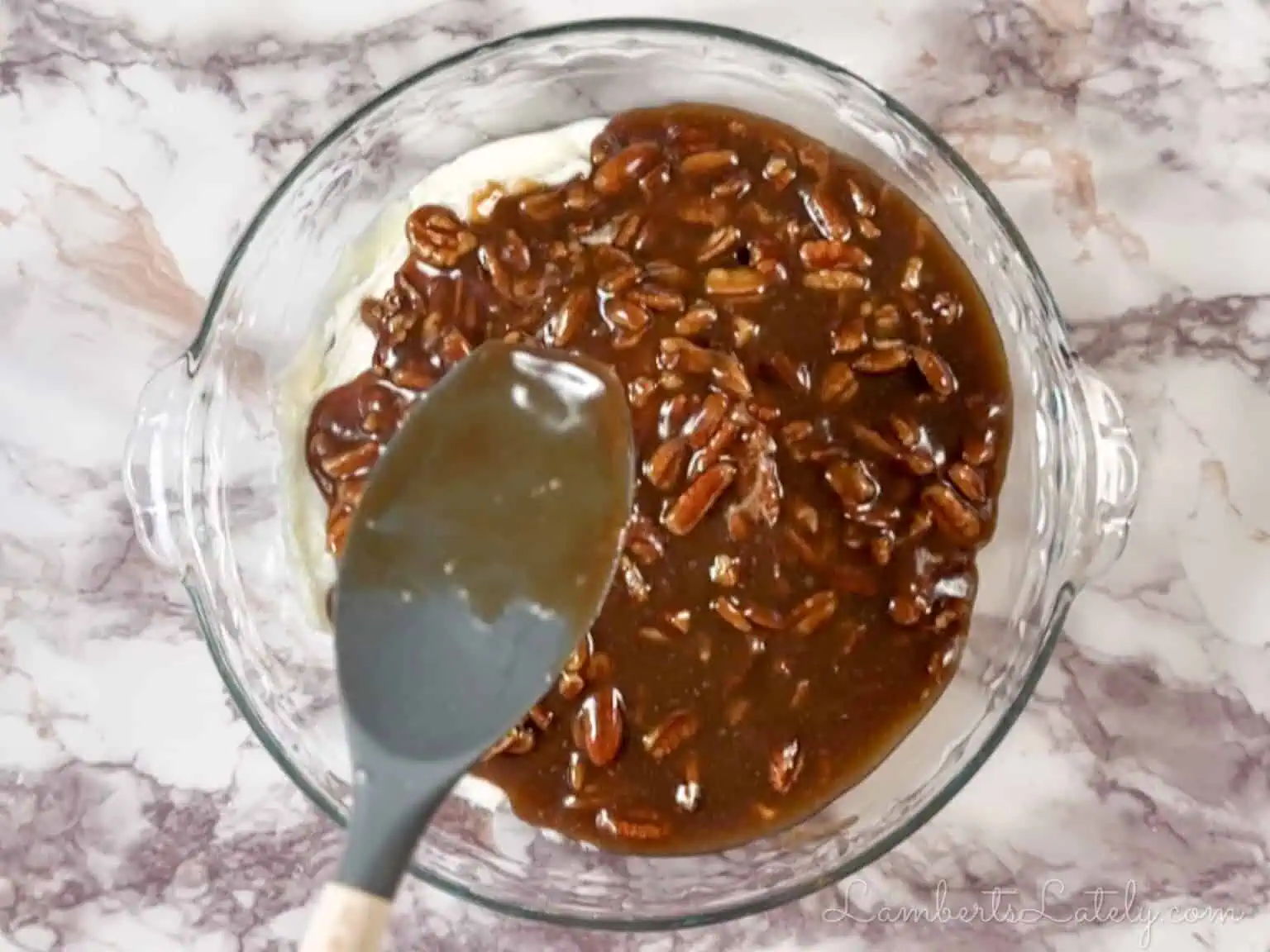 spreading gooey pecan pie mixture over the cream cheese base in the pie dish.