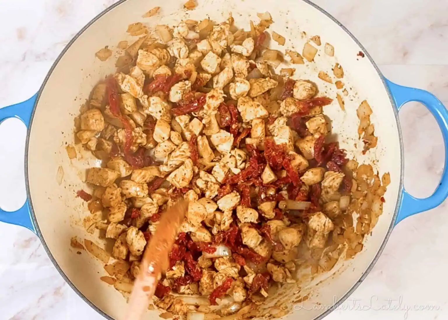 cooking chicken, sun-dried tomatoes, and onion in a large pot.
