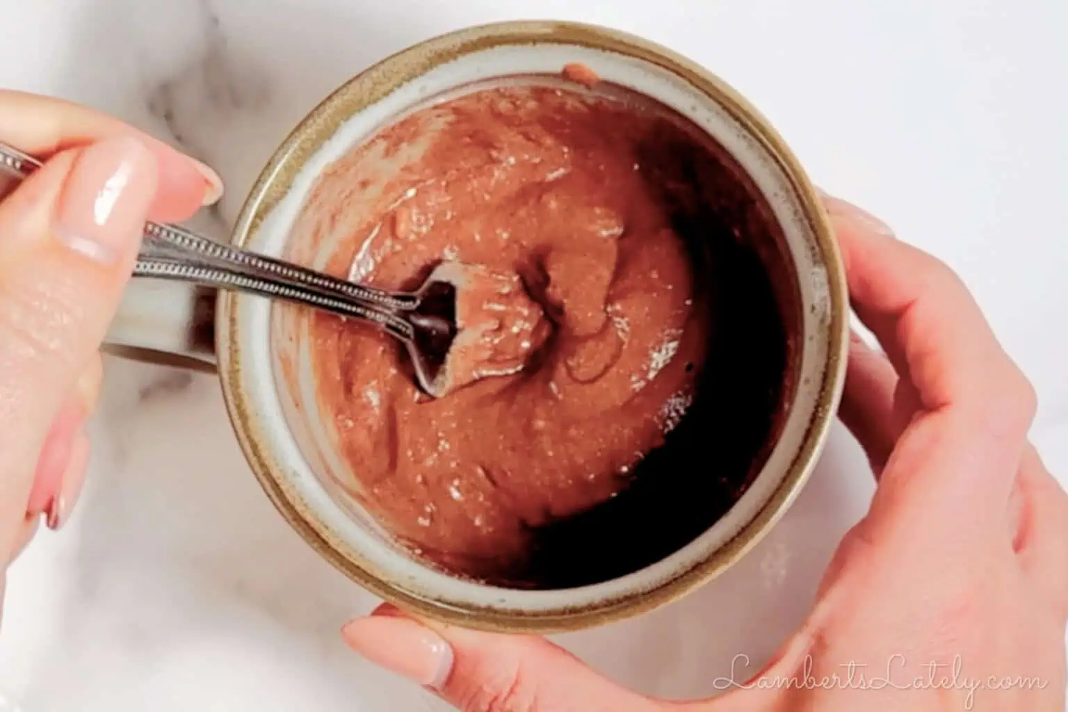 stirring chocolate cake batter in a mug.
