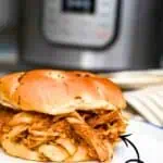 Pressure cooker BBQ chicken sandwich with shredded chicken on a bun.