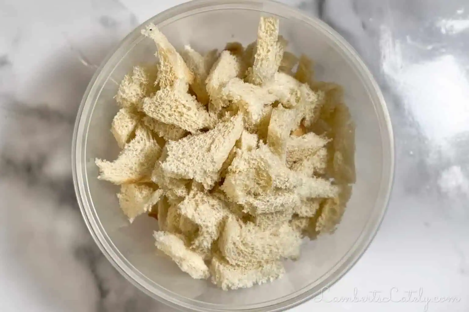 torn white bread, crusts removed, in a clear bowl.