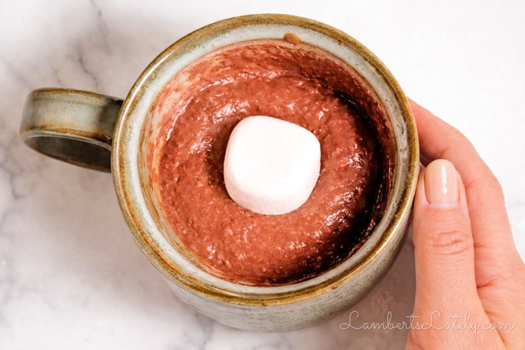 pressing a jumbo marshmallow into the center of the hot cocoa mug cake batter.