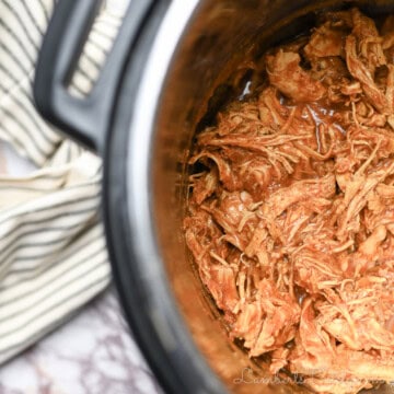 barbecue chicken covered in sauce in an instant pot, towel beside it.