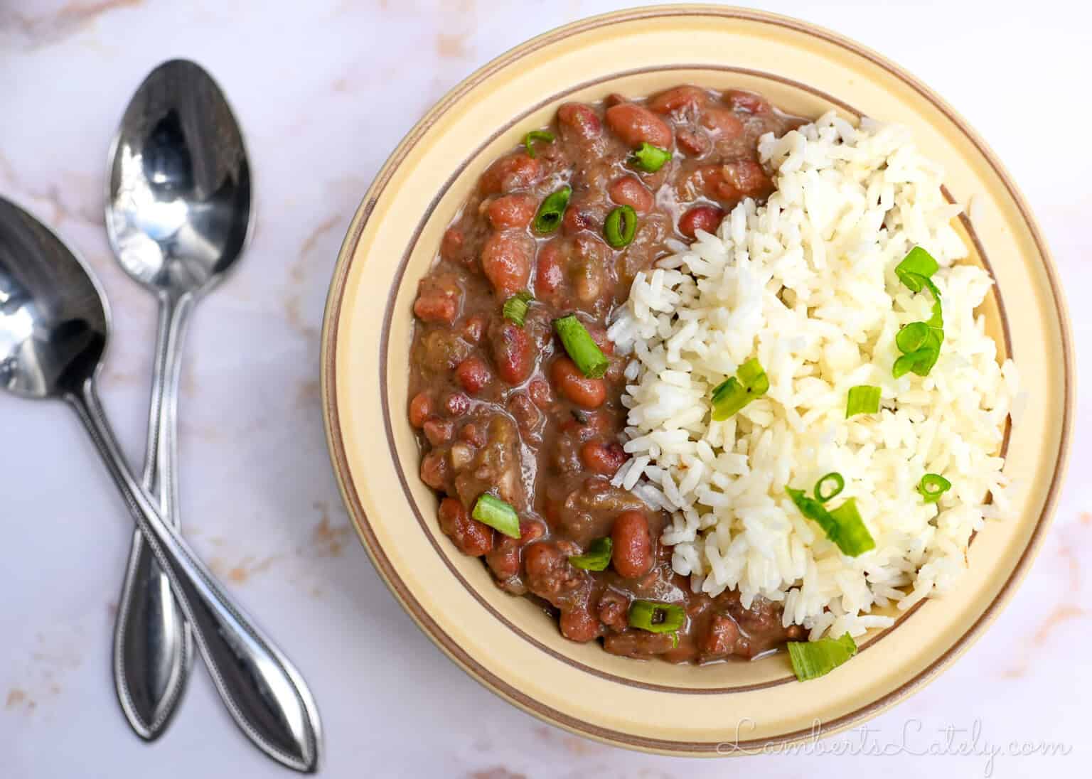 bowl of red beans and rice next to 2 spoons.