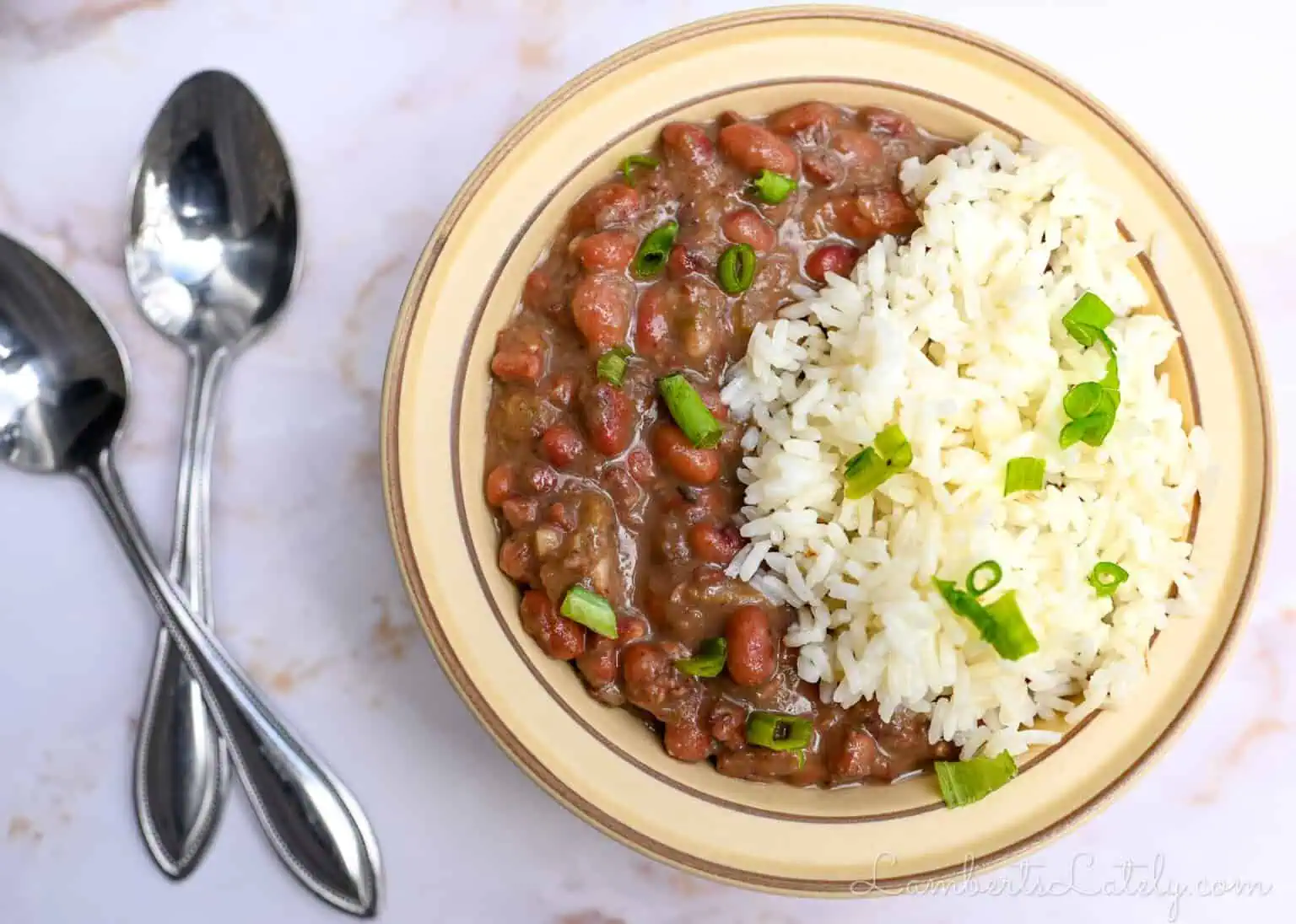 bowl of red beans and rice next to 2 spoons.