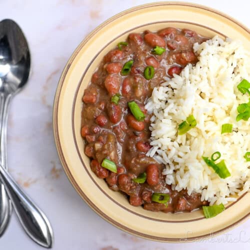 bowl of red beans and rice next to 2 spoons.