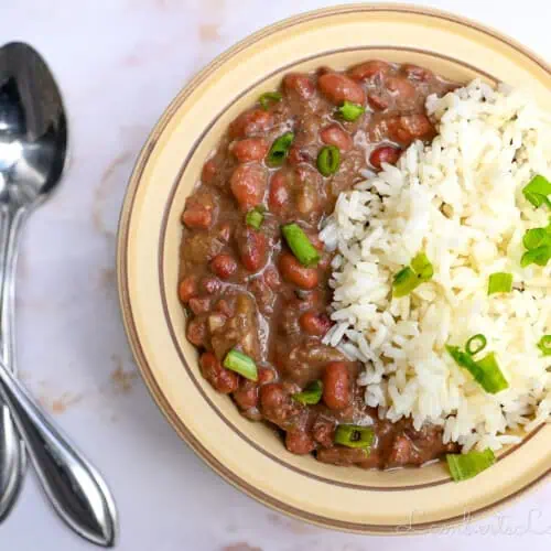 bowl of red beans and rice next to 2 spoons.