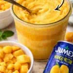 Creamy mango sorbet in a glass jar with a spoon, labeled 2 ingredients, on a wooden surface.
