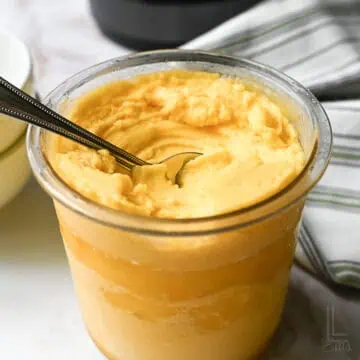 a ninja creami pint container of mango sorbet, after spinning, with a spoon.
