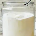 Homemade laundry detergent powder in a glass jar with handwritten text and decorations.