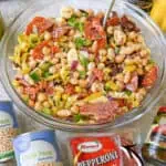 Close-up of a dense bean salad with vegetables and meat in a glass bowl.