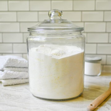 large glass jar of diy laundry deteregnt on a counter, surrounded by laundry supplies.