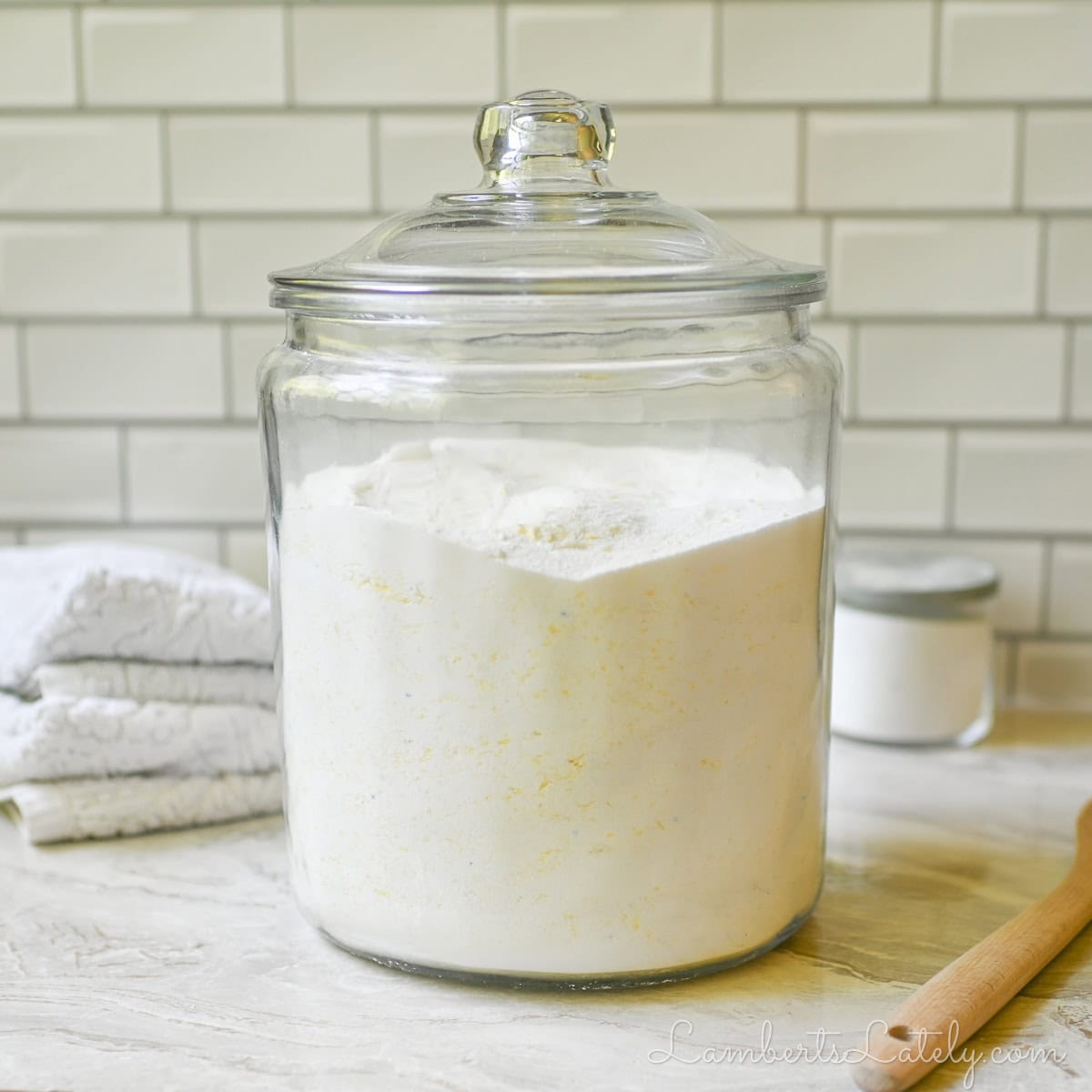 large glass jar of diy laundry deteregnt on a counter, surrounded by laundry supplies.