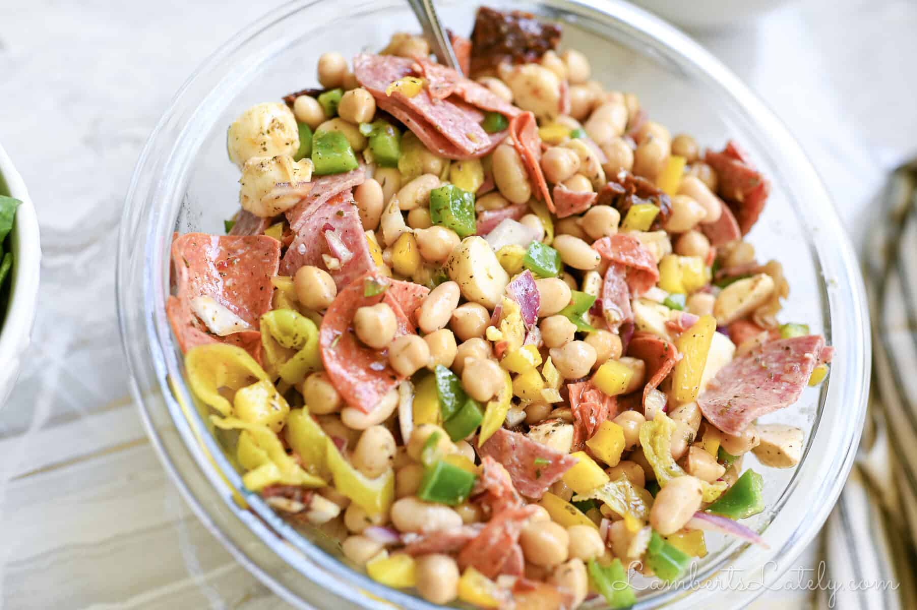 Bacon ranch bowtie pasta salad with cherry tomatoes and peas in a white bowl.