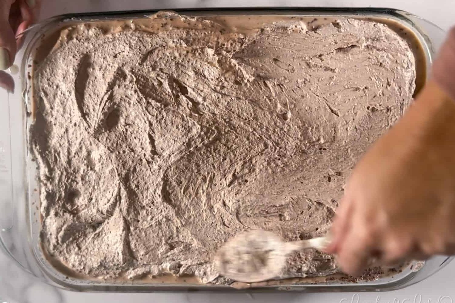 spooning chocolate whipped cream over cake.