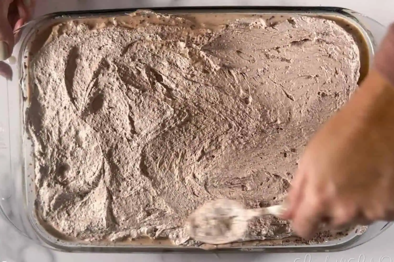 spooning chocolate whipped cream over cake.