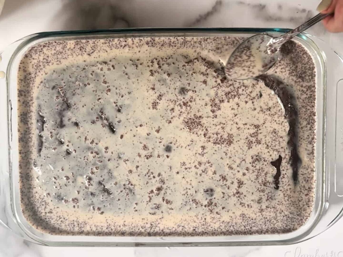 pouring tres leches milk mixture over chocolate cake.