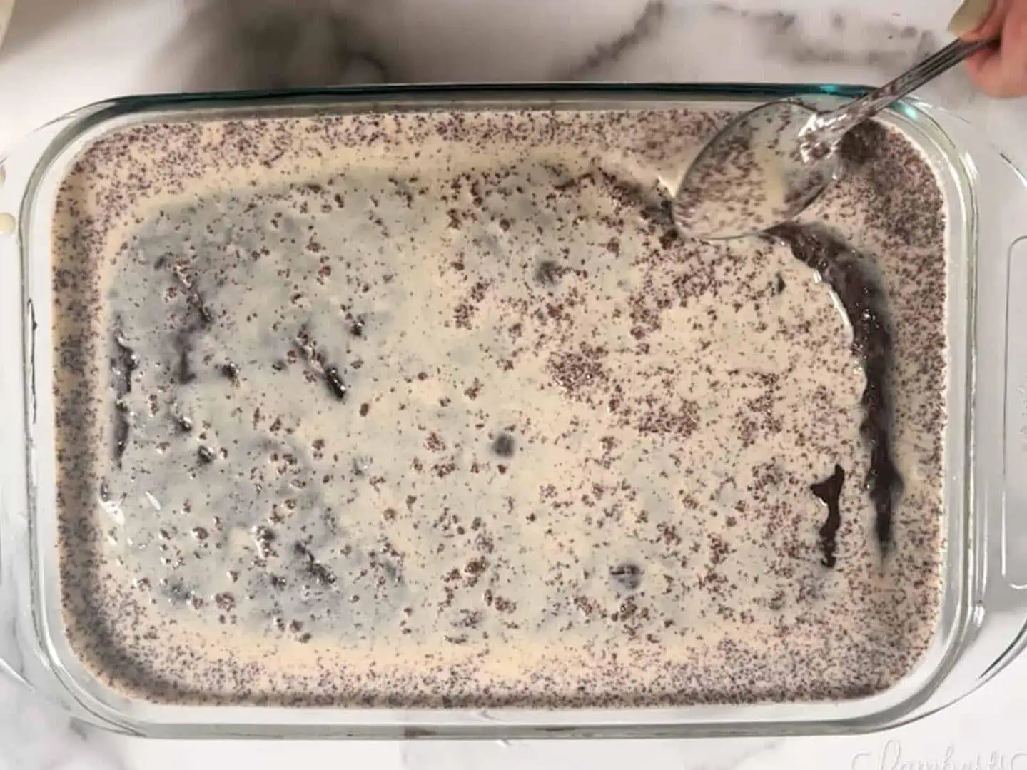 pouring tres leches milk mixture over chocolate cake.