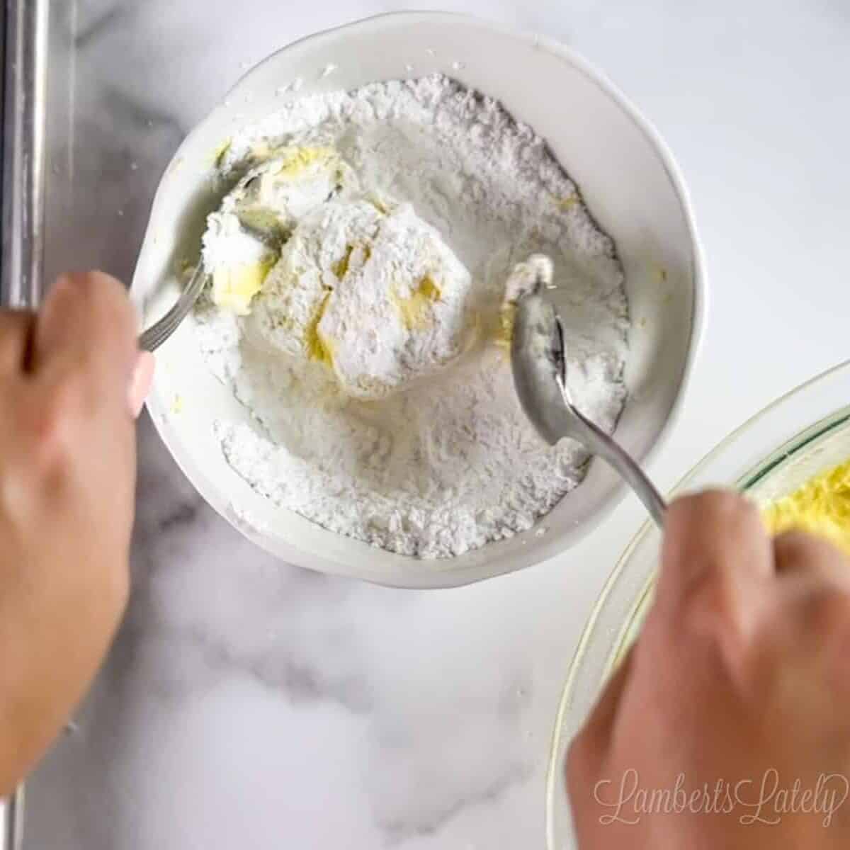 rolling a ball of cookie dough in a bowl of powdered sugar.