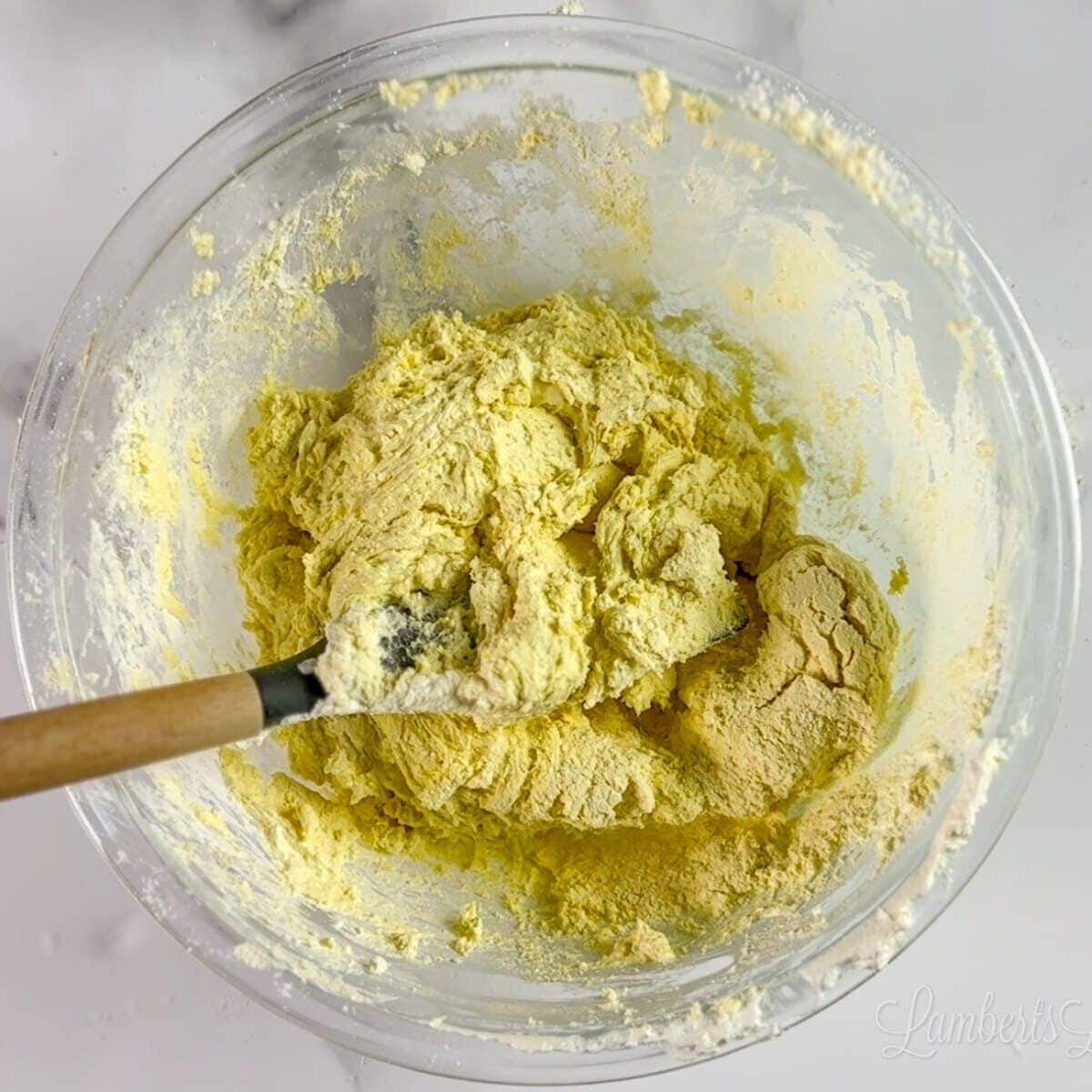 yellow cookie dough in a clear glass bowl.